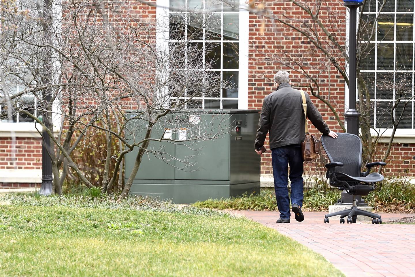 A man wheels a chair behind him as he leaves campus