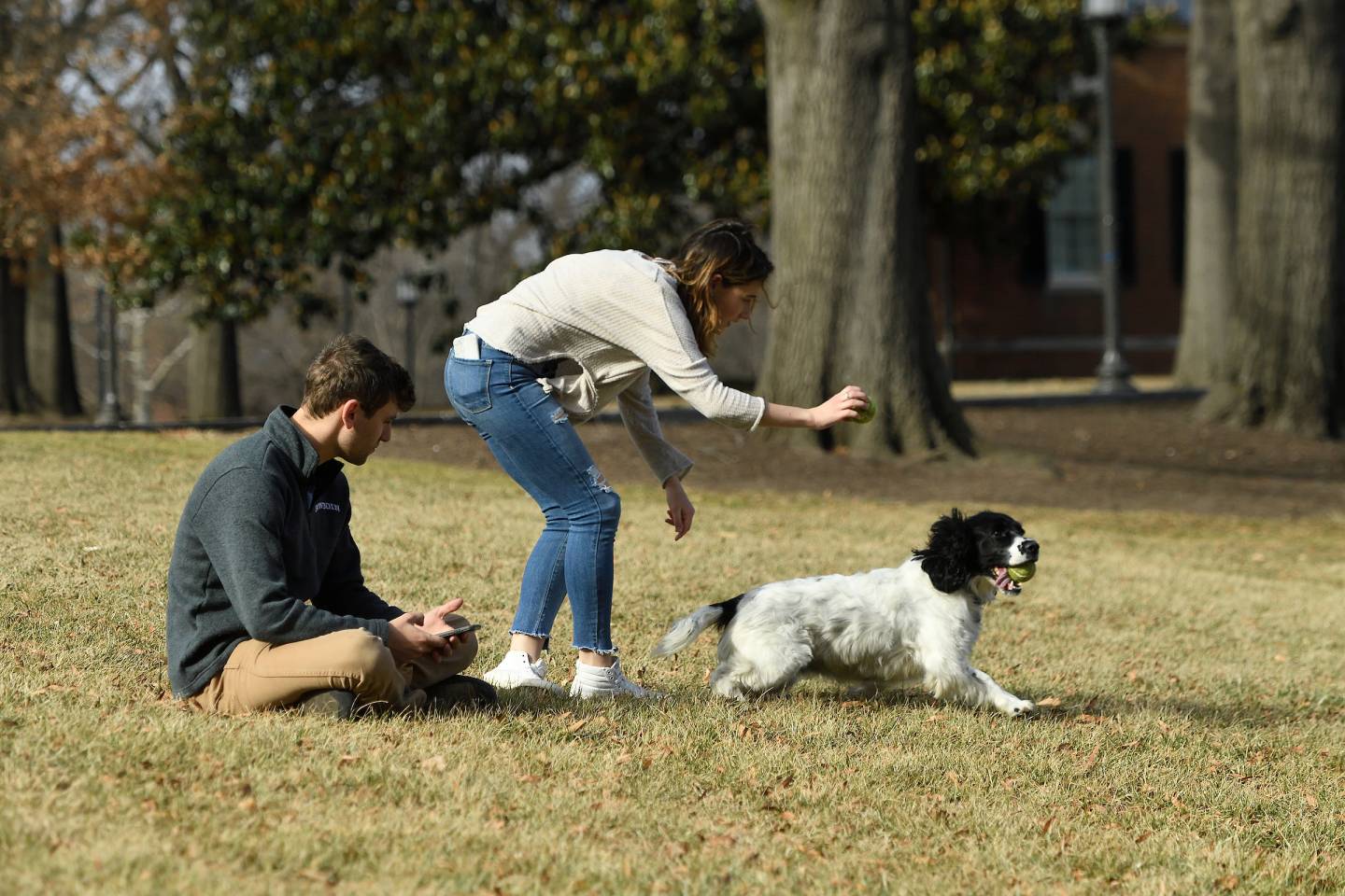 Two people play fetch with a dog