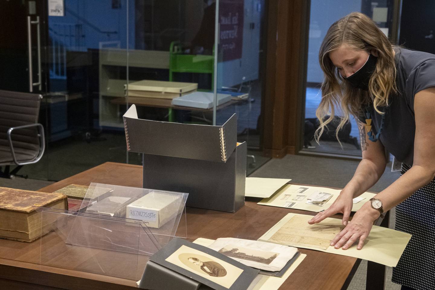 A woman bends over a table to discuss artifacts and images