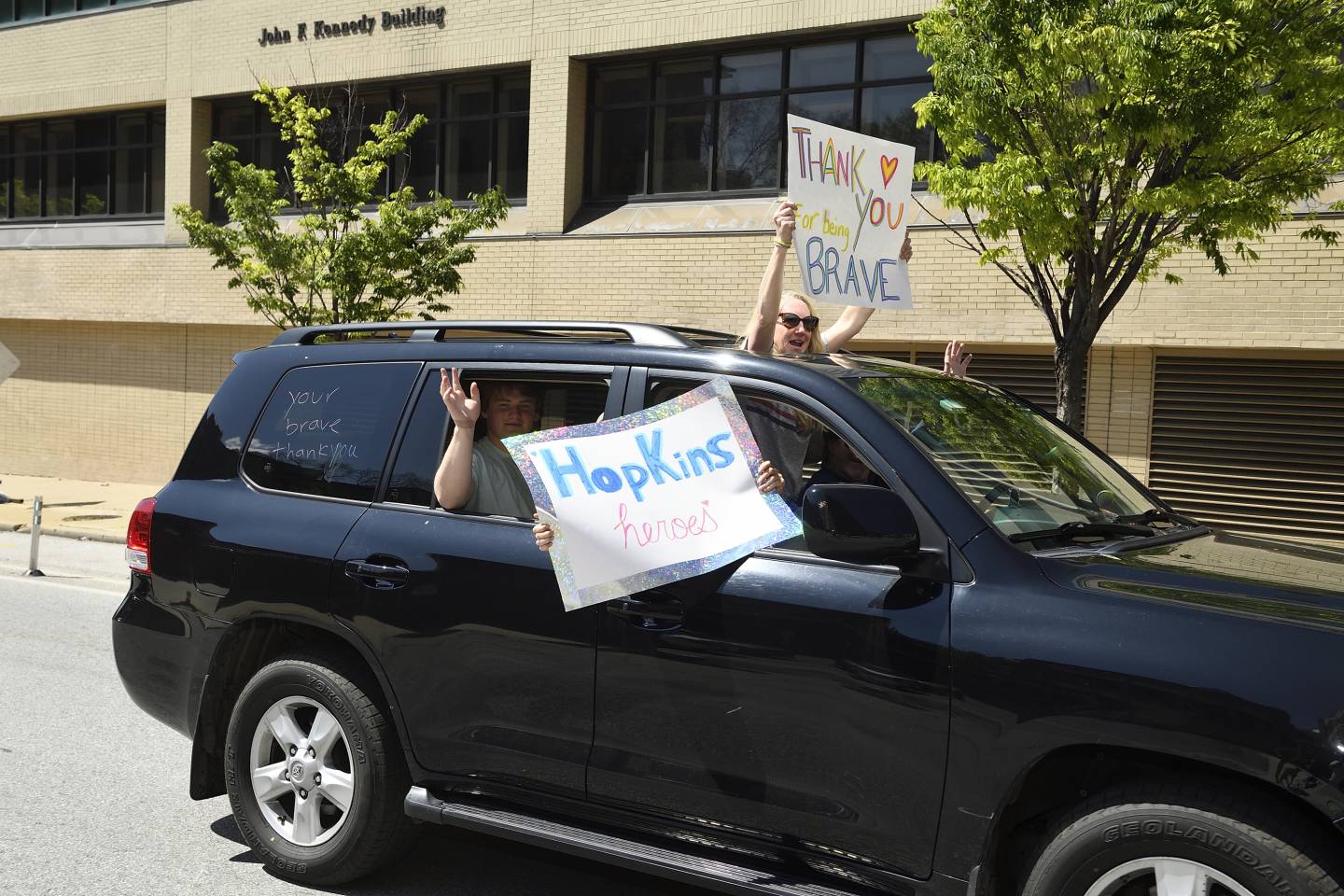 People in a car wave signs thanking health care workers