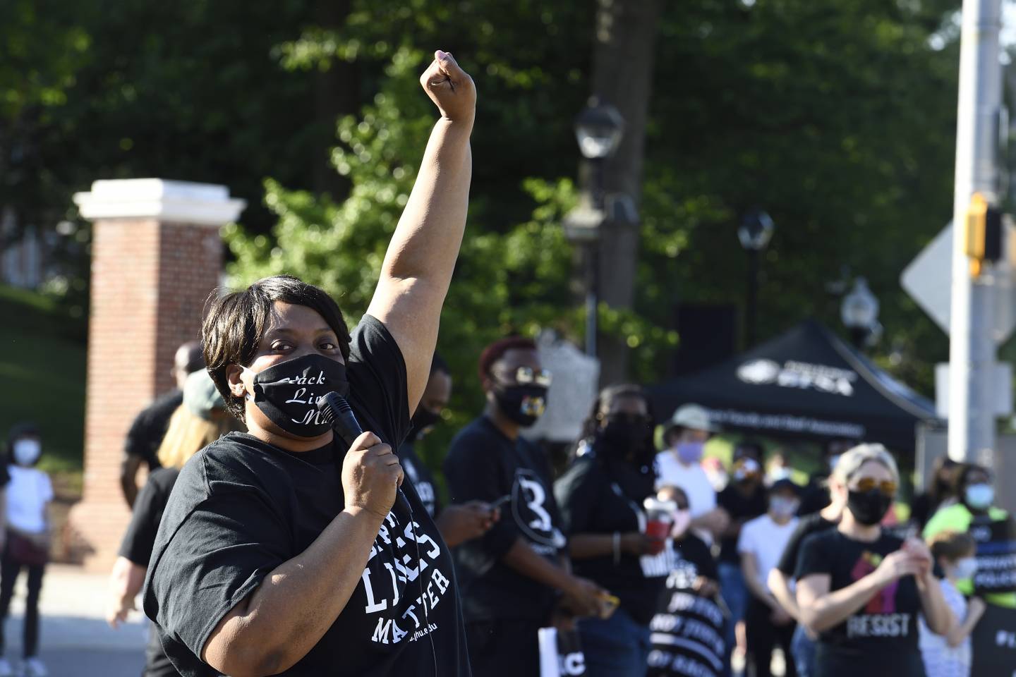 A masked woman with a microphone raises a fist