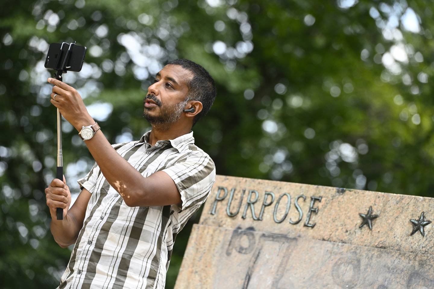 A man with a selfie stick speaks into a camera