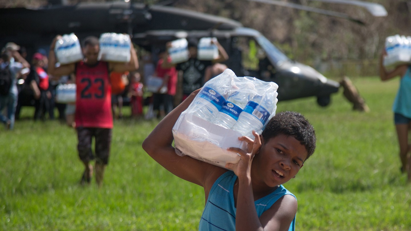 A boy carries a case of water A boy carries a case of water