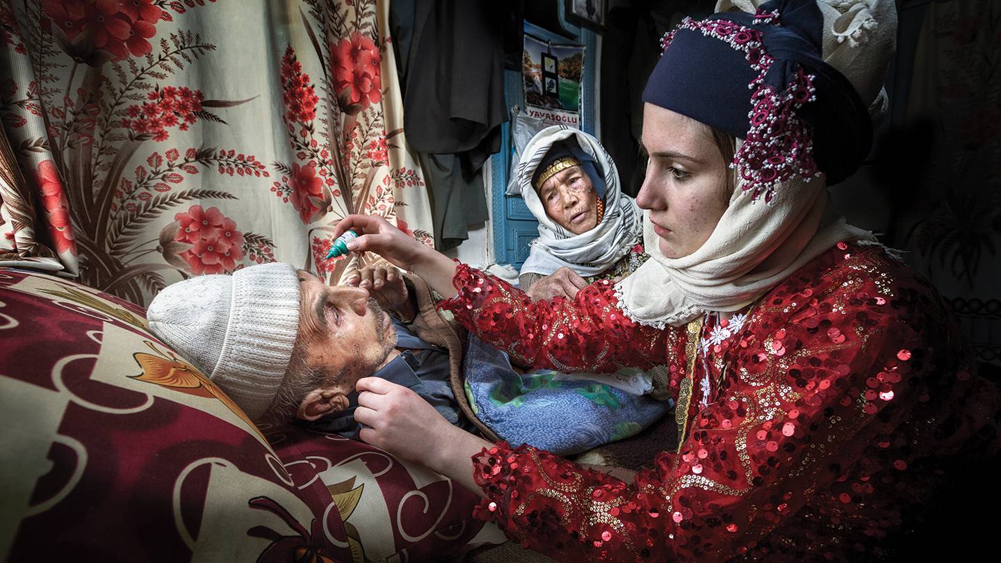A woman administers eyedrops to her grandfather A woman administers eyedrops to her grandfather