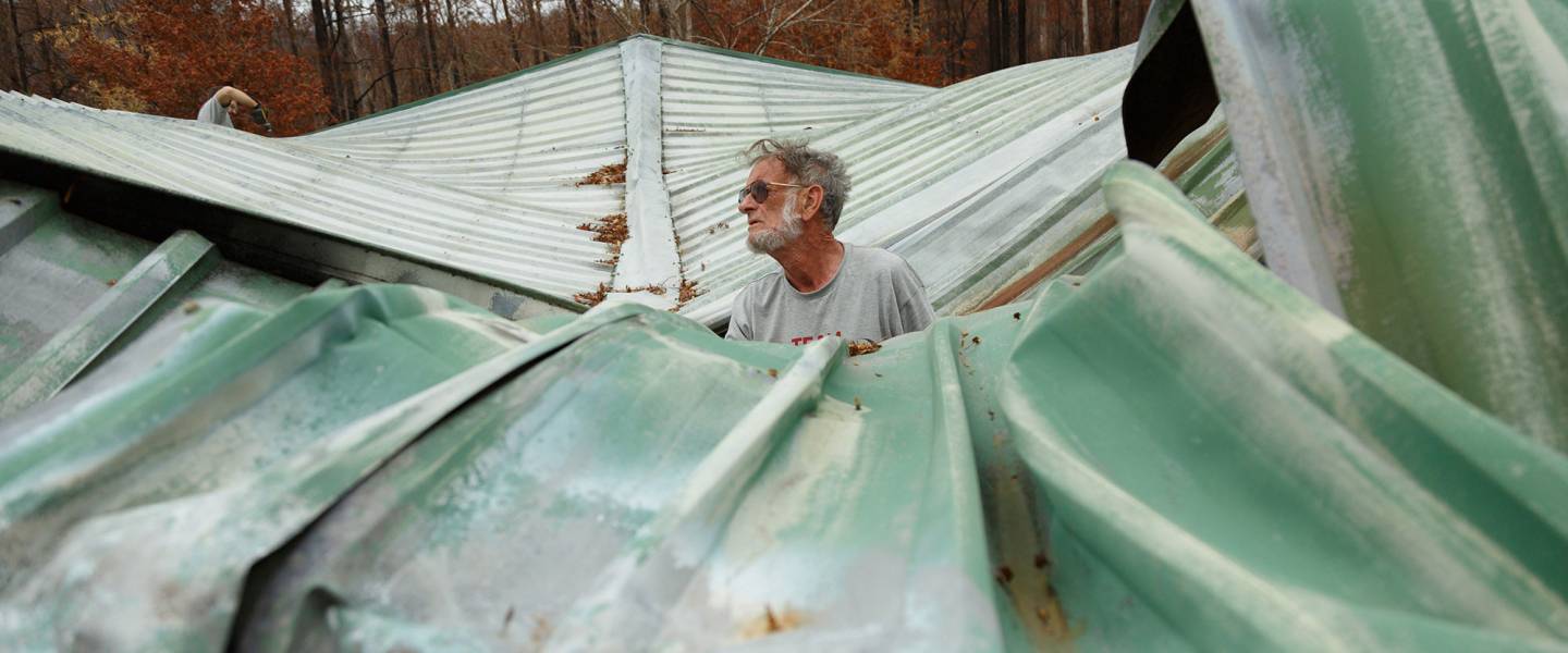 A Team Rubicon volunteer stands among the remnants of a destroyed house