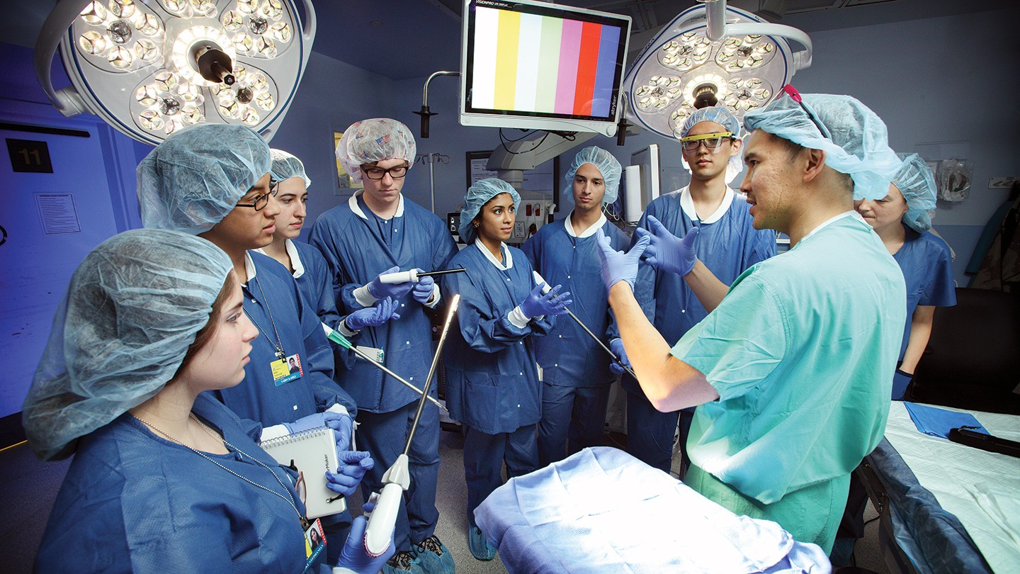 A physician in scrubs instructs a group of undergrads A physician in scrubs instructs a group of undergrads