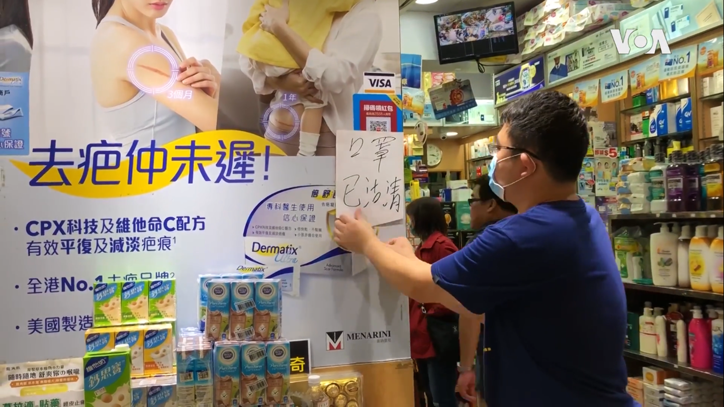 A pharmacy employee hangs a sign written in Chinese
