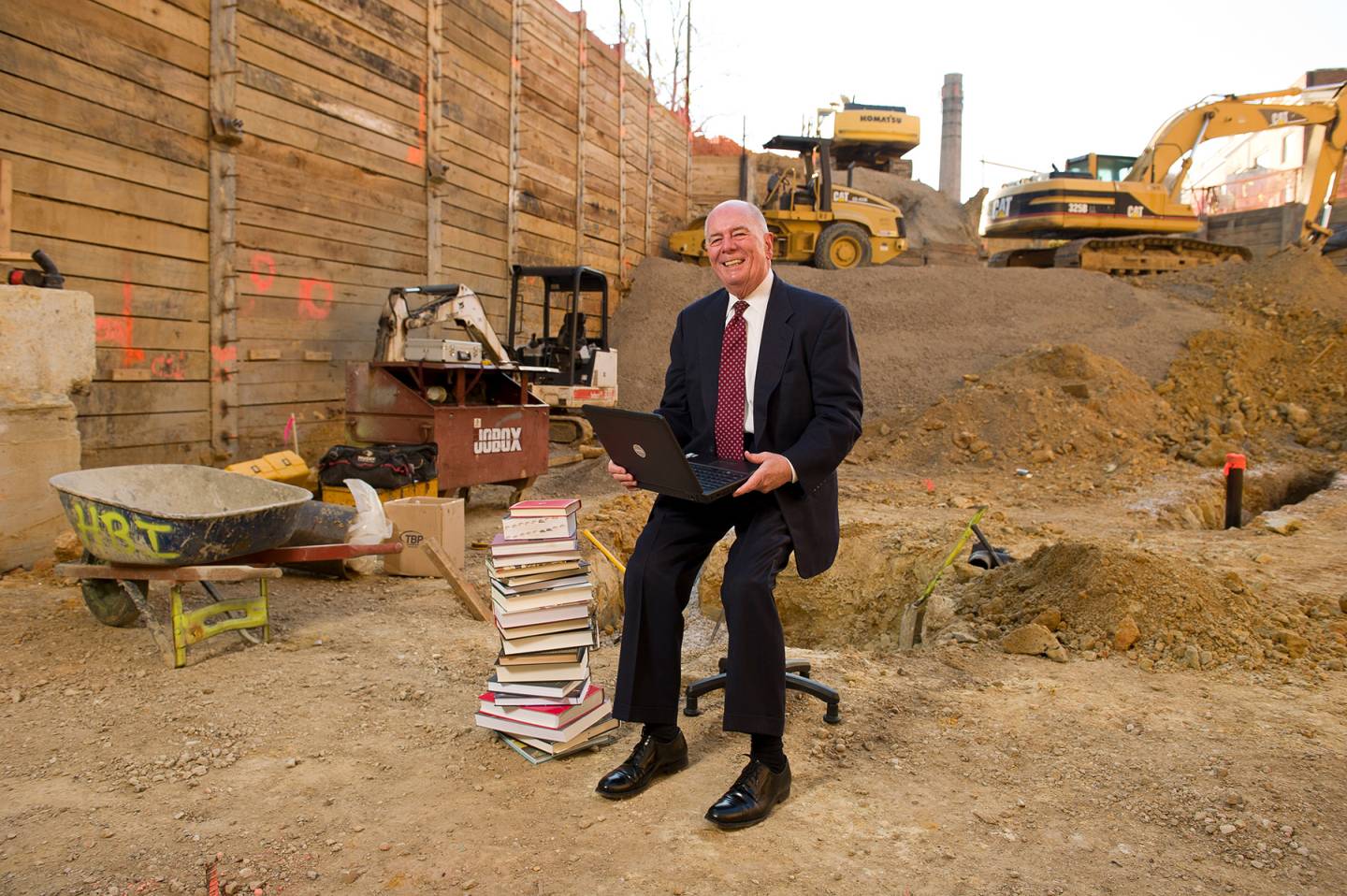Winston Tabb with laptop and stack of books in construction footprint