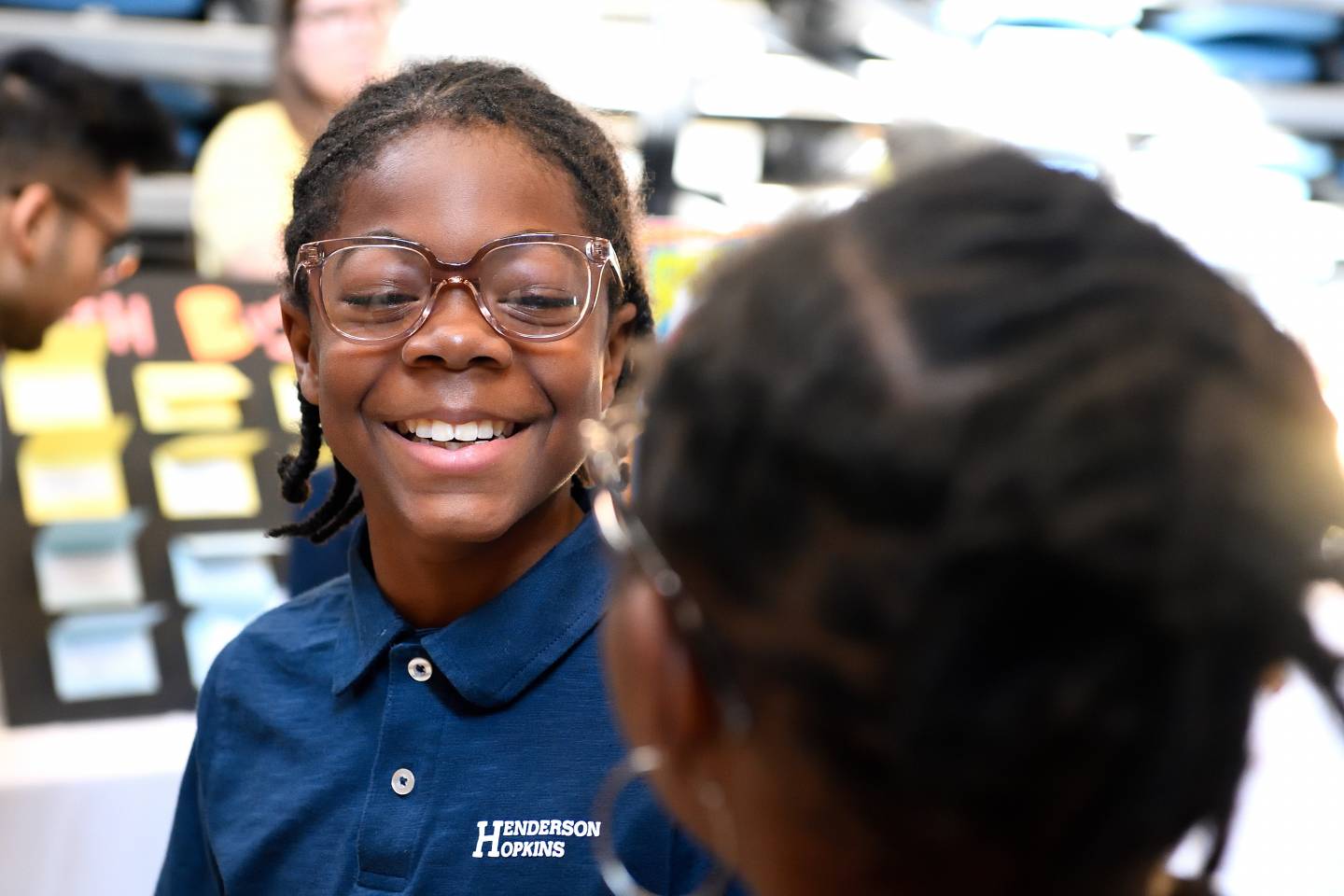 An elementary school student smiles while trying on eyeglasses