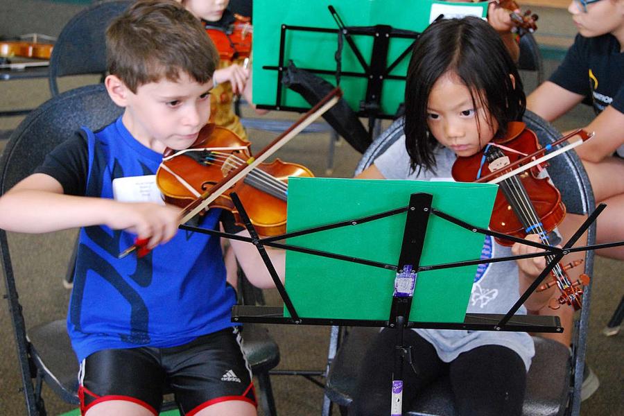A young girl and boy play their violins in an Allegro Strings at Peabody class