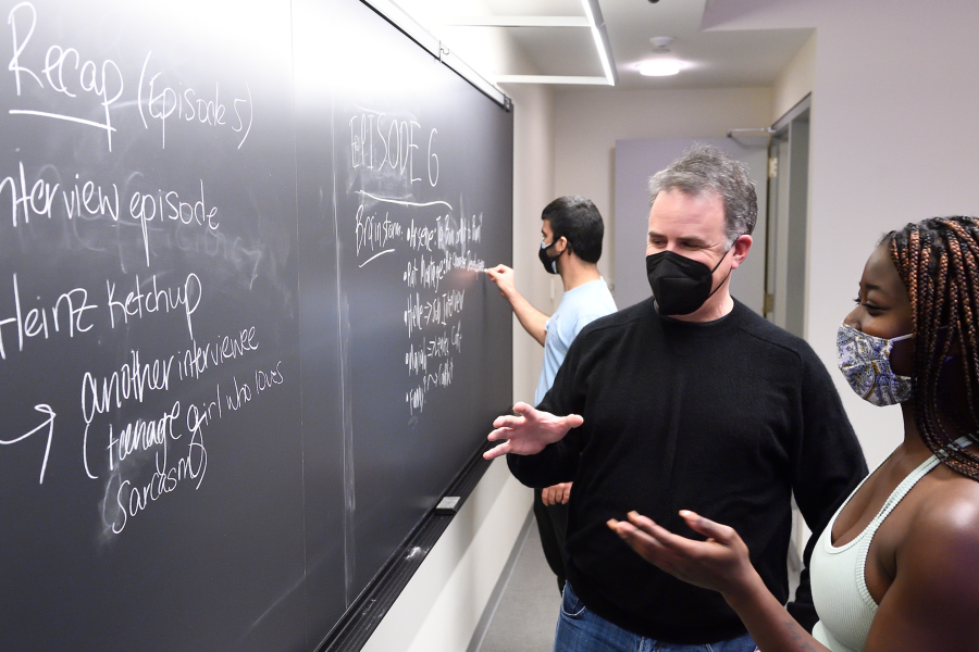 Two people look at writing on a chalkboard