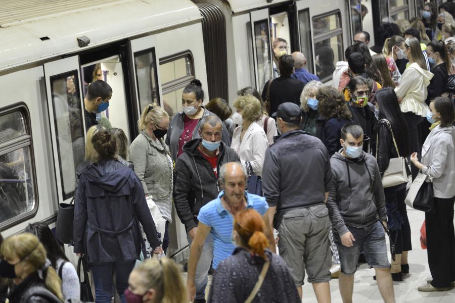 Train passengers both with and without protective masks crowding to get on and off subway station platform