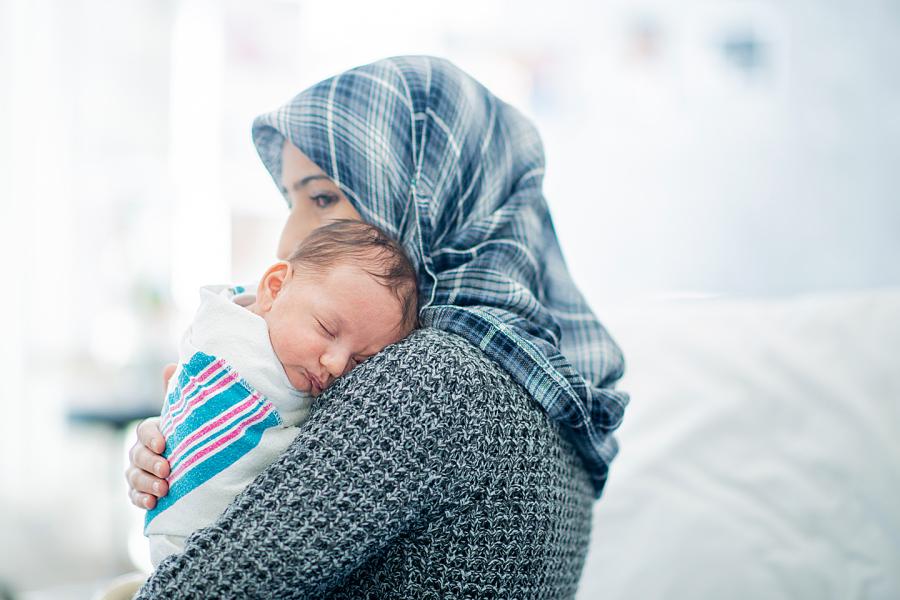 Woman wearing a hijab holds her newborn in the hospital.