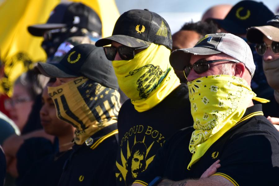 Members of the Proud Boys attend a rally wearing yellow bandanas and gaiters over their faces