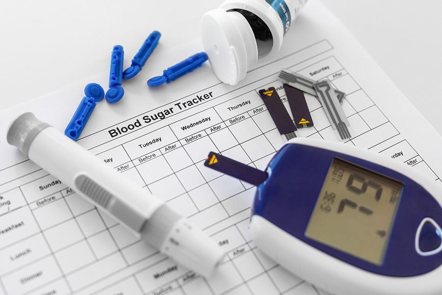 Instruments for checking blood sugar levels lying on a chart for tracking information about the readings 