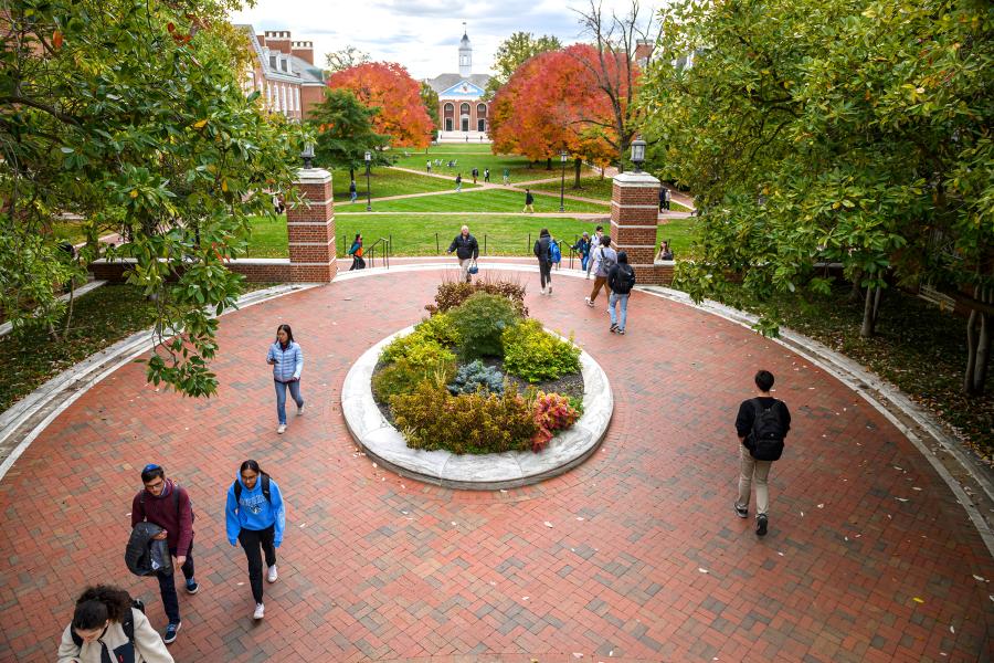 Students walk on a red brick campus walkway