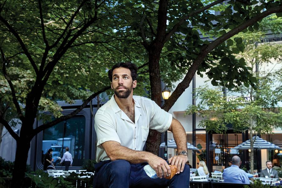 Paul Rabil sits on a bench holding a croissant
