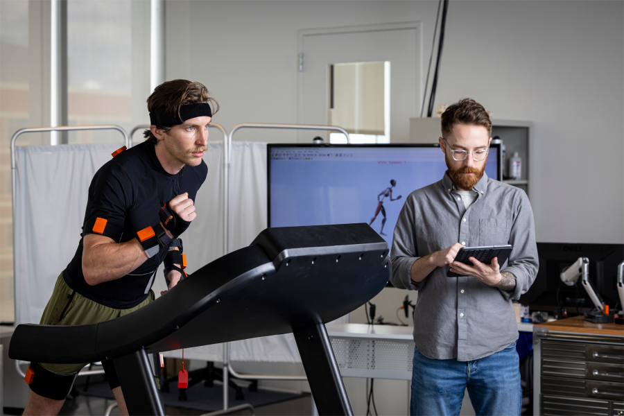 A person runs on a treadmill while another person tracks their movement