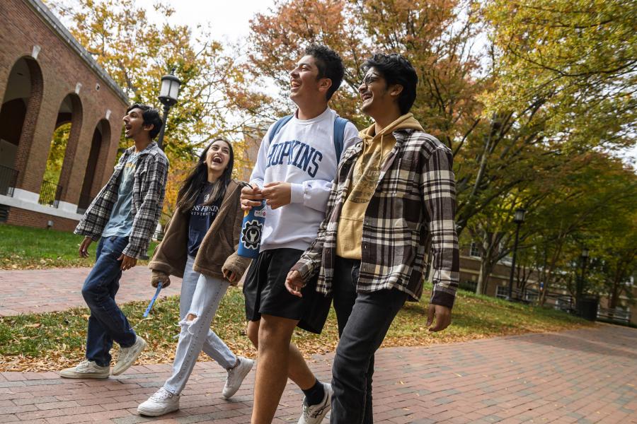 Students walk and laugh on a fall day on the Homewood campus