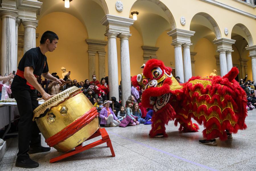 A person plays a drum while a giant puppet dances