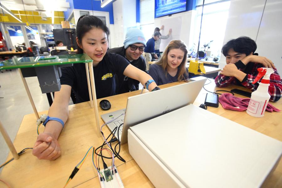 Four students work together at a laptop computer