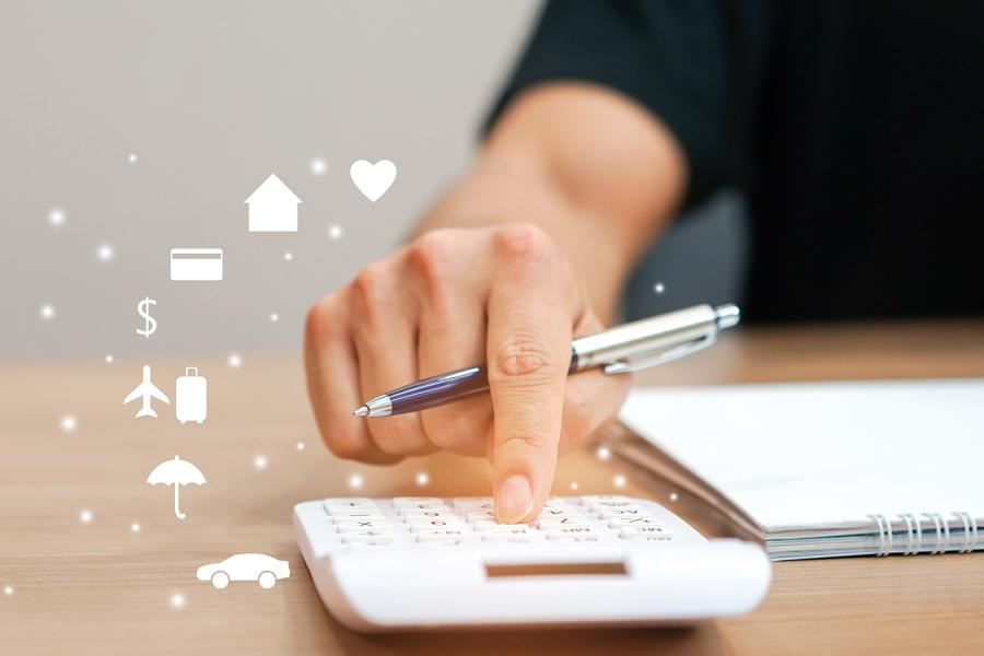 A hand is pressing buttons on a calculator and is surrounded by symbols of items such as a house and car that would be considered in making a budget.