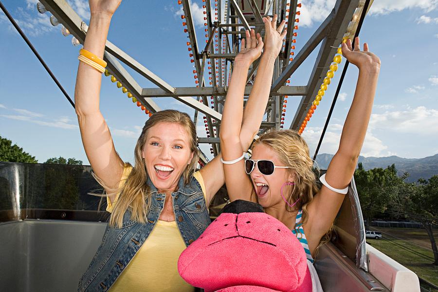 Mother and daughter with hands raised as they ride a roller coaster