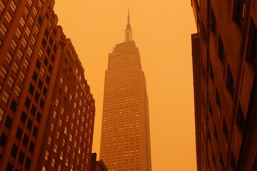 The Empire State Building in New York is seen through a thick, orange haze