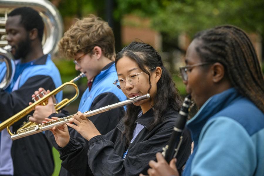 A row of students play the tuba, trumpet, flute, and clarinet