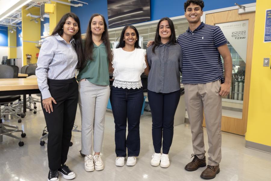 Five student team members pose for a photo in a lab setting