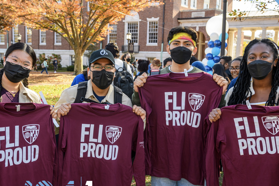 Four students pose for a photo holding maroon FLI Proud shorts