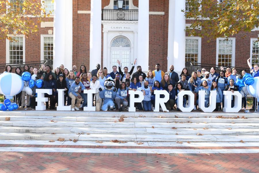 A group stands behind large letters that read 