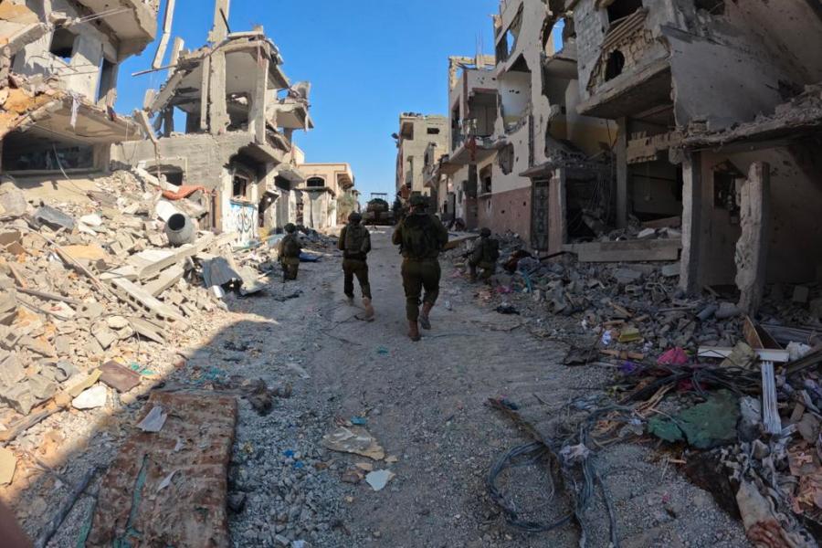 Three soldiers walk among the ruins of buildings in Gaza