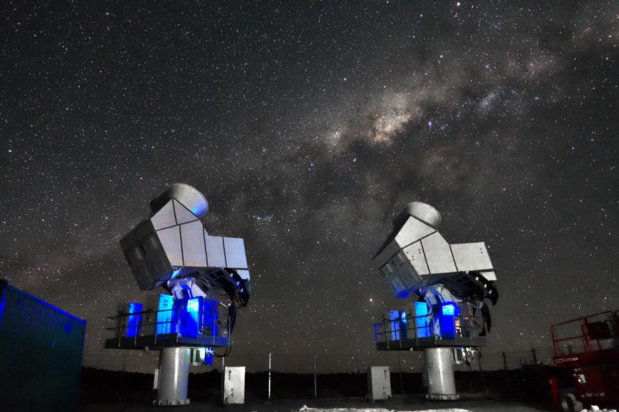 A nighttime photo of the CLASS telescopes with a starry sky and milky way galaxy in the background