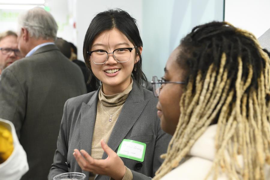 An adult smiles at another adult during a networking event.