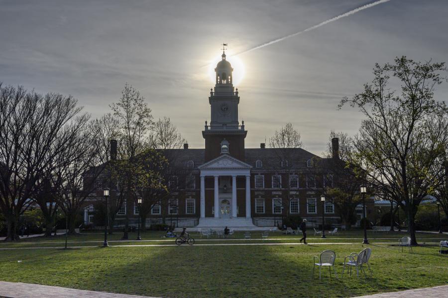 Photo of Gilman Hall in which the sun is perfectly aligned with the spire.