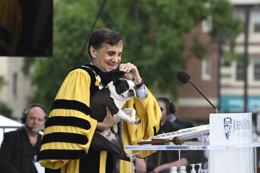 Ron Daniels holds his dog up to the microphone at the JHU Commencement ceremony.