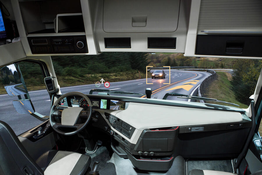 Rendering of the interior of an autonomous vehicle. No one is seated at the steering wheel, but the car's computer system has identified another car on the road.