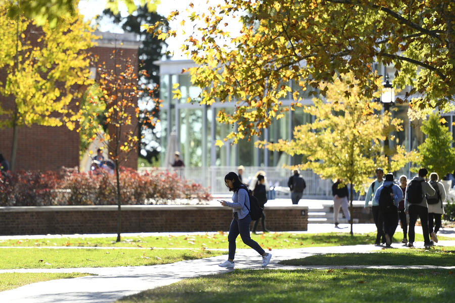 Students walk across campus under fall foliage