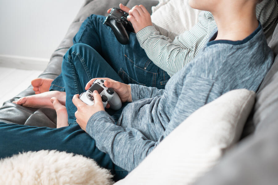 Two people play video games on a couch.