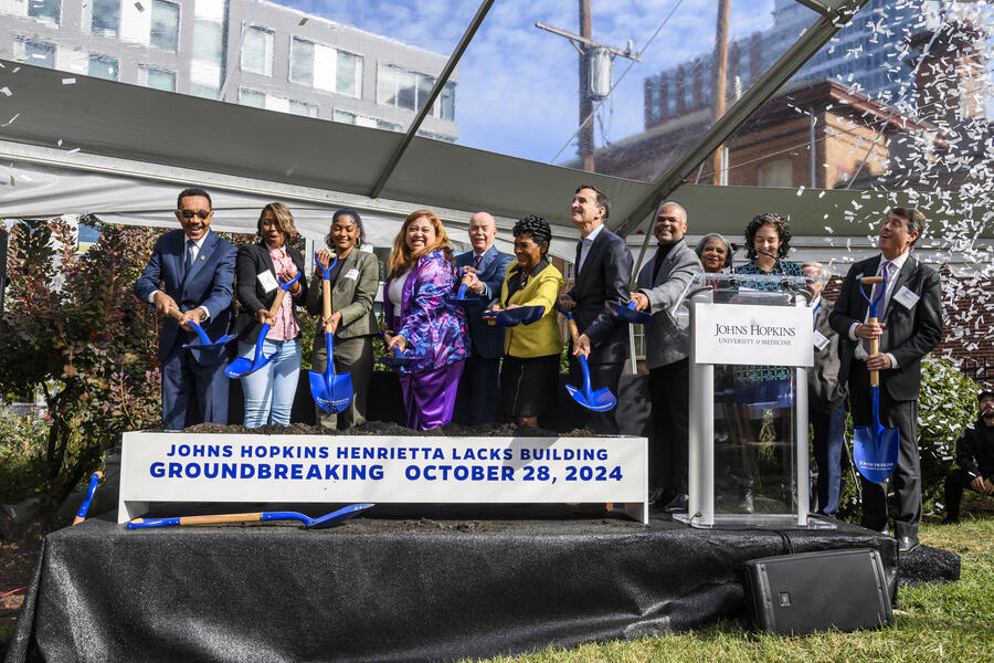 A group of people shovel dirt at a ceremonial groundbreaking event