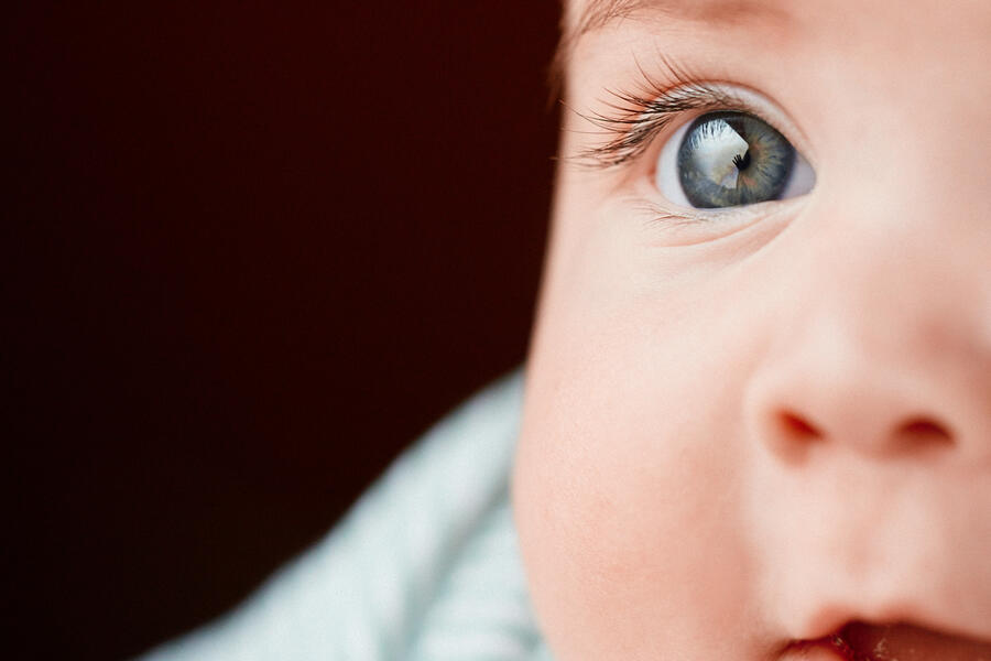 A baby with blue eyes looking away.