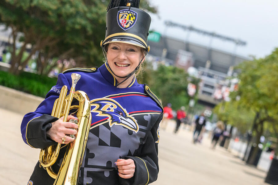 Gigi Gronvall wearing a purple and black Marching Ravens uniform and holding the baritone she plays in the band.