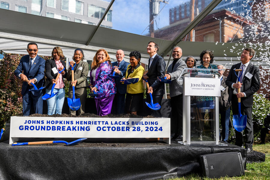 A group of people shovel dirt at a ceremonial groundbreaking event