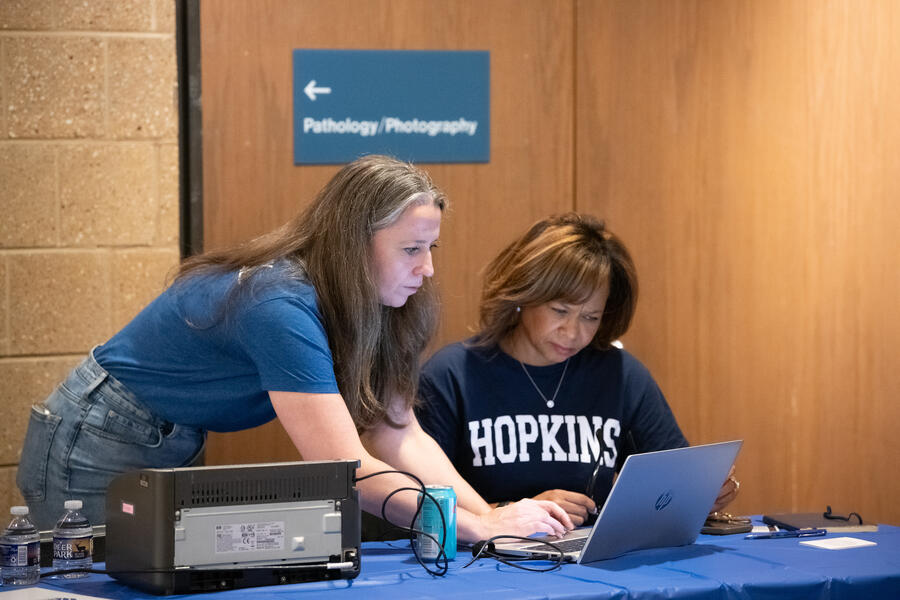 Meaghan McDermott, left, and Maria Harris Tildon at a table looking at a laptop