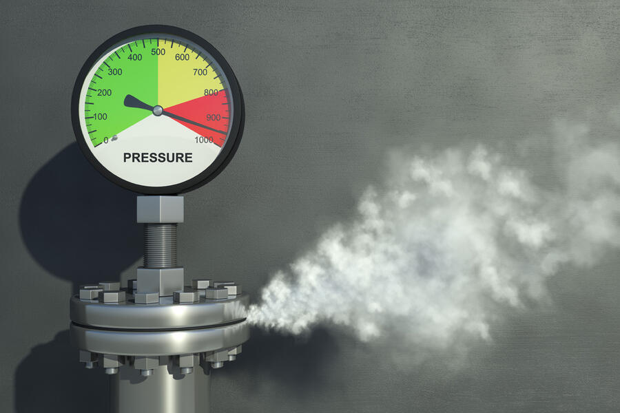 A pressure gauge in the red zone with steam coming out of a pipe