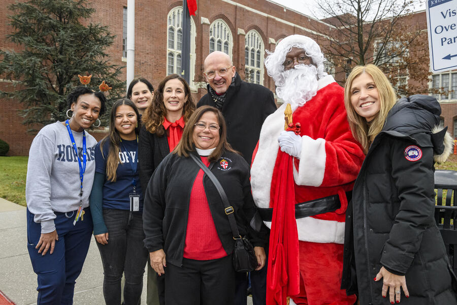 Eight people pose for a group photo outside. One is wearing a Santa costume.