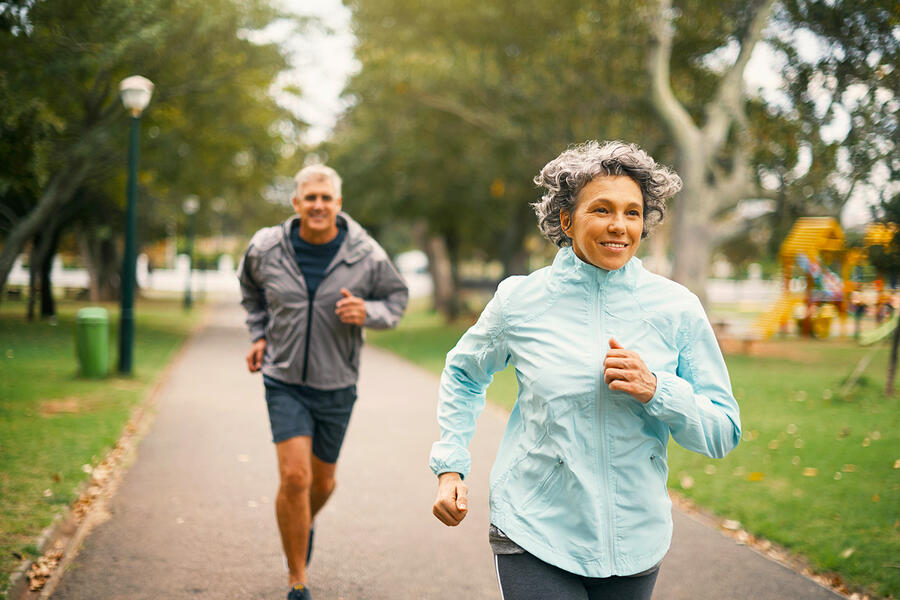 Middle-aged man and woman running on a path in a park