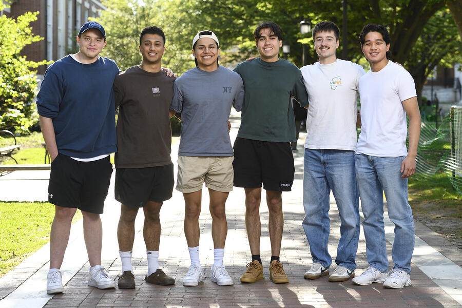 A group of six college students smile for the camera with their arms around each other.