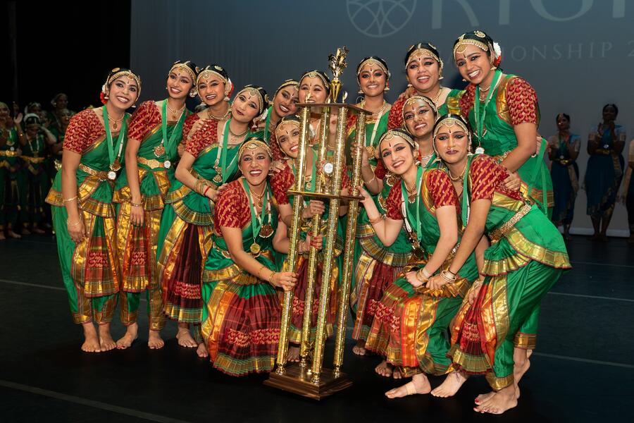 JHU Shakati poses with their trophy after winning nationals. They are dressed in fancy Indian clothing.